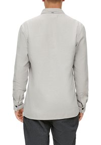 Camicia grigia chiaro a maniche lunghe con colletto e polsini abbottonati. Tessuto morbido e design su misura, con orlo arrotondato nella parte inferiore.
