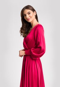 Fuksjowa sukienka z długimi, bufkami rękawami i węzłem w talii. Gładki, satynowy materiał z płynną sylwetką.