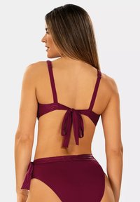 Bordowy bikini składający się z regulowanych ramiączek, z zapięciem na plecach i dopasowanymi, wysokimi majtkami. Gładka struktura z delikatnymi, prążkowanymi akcentami.
