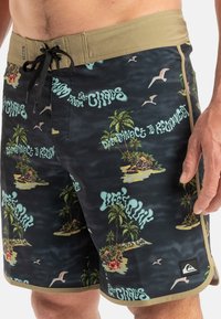 Schwarze Badehorts mit einem bunten tropischen Druck von Palmen und Inseln, einem khakifarbenen Bund und schwarzen Kordelzugakzenten.