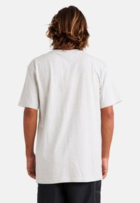 Camiseta de manga corta en gris claro con un corte relajado y una textura suave, que incluye un cuello redondo y una parte trasera lisa sin estampados ni adornos.