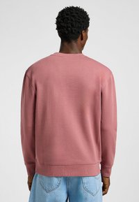 Pitkähihainen pyöräkaula-aukko neuletakki pölypinkkinä. Puuvillasekoitekangas, ribbikaulus ja hihan suut, rento malli. Korostettu minimikoristeluilla.