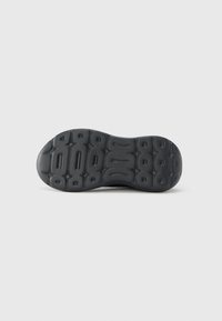 Suela de zapato de goma negra con superficie texturizada. Presenta patrones de áreas elevadas y ranuras para tracción y flexibilidad.