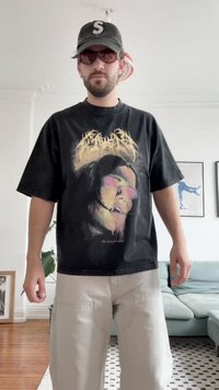 Čierne oversized tričko s grafickým potlačou tváre s farebnými detailmi. Skombinované s svetlými béžovými cargo nohavicami a čiernym čiapkou.