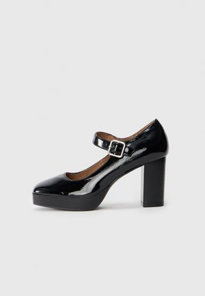 Black patent leather high-heeled Mary Jane shoe with a square buckle strap and a block heel, featuring a rounded toe and a platform sole.