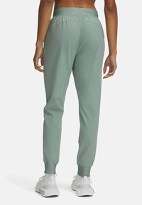 Ljusgröna sportbyxor med elastiskt midjeband, avsmalnande ben och muddar. Slät tyg med sidofickor och minimala sömmar.