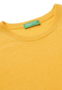Žlutý pletený svetr s kulatým výstřihem a žebrovanými manžetami. Zelená visačka s nápisem "United Colors of Benetton." Měkká textura.