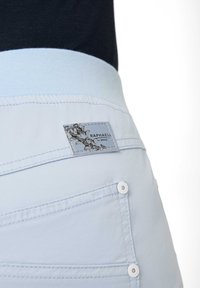 Lichtblauwe tailleband met contrasterende lichterblauwe band. Decoratieve stiksels, labeldetail met bloemenontwerp en witte knoopaccenten op de zakken.