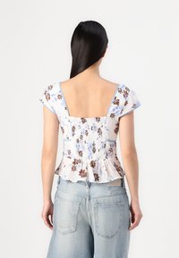 Top peplum floreale in tessuto leggero; presenta un motivo blu e marrone, scollatura quadrata e maniche corte con bordi arricciati.