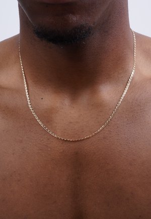 Gold chain necklace with a twisted design, resting on bare skin, featuring a smooth, shiny surface and subtle reflections.