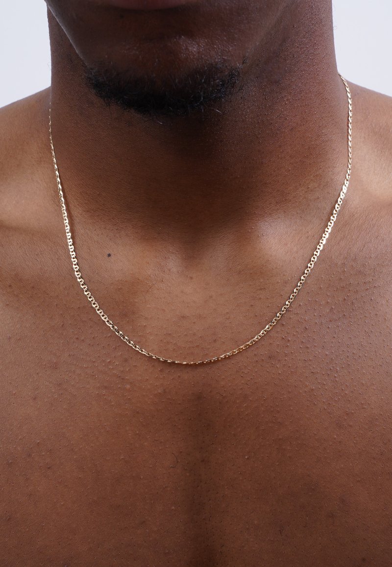 Gold chain necklace with a twisted design, resting on bare skin, featuring a smooth, shiny surface and subtle reflections.