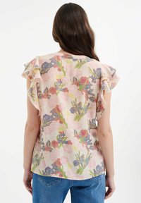Bluse mit Blumenmuster aus leichtem Stoff, mit rüschensetzenden kurzen Ärmeln, pastellrosa Hintergrund und buntem Blumendesign.