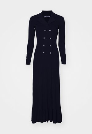 Vestido largo de punto negro con canalé, con un delantero de doble botonadura, cuello notch y dobladillo acampanado. Presenta botones en tono plateado en las mangas.