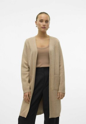 Beige langer Cardigan mit offenem Frontbereich, gerippten Bündchen und zwei Fronttaschen, aus weichem Material, kombiniert mit einem eng anliegenden beige Oberteil und schwarzen Hosen.