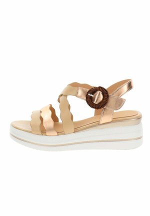 Sandale compensée beige et or rose métallique avec des brides festonnées, une boucle circulaire marron et une semelle plateforme blanche.