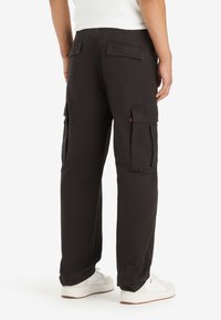 Svarta cargobyxor med rak passform, med lapplådor på låren och baksidan, tillverkade av slitstarkt tyg, designade för funktionalitet och komfort.