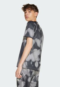 Šedé športové tričko s motívom tie-dye v tmavých a svetlých odtieňoch, krátke rukávy a detaily plochého švu.