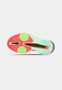Semelle d'une chaussure de course Nike Flyplate en vert clair et rouge avec découpes noires et patins texturés antidérapants.