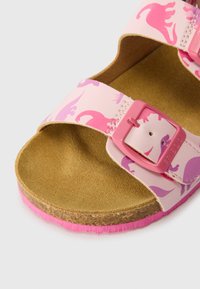 Infradito rosa con motivi di dinosauro, dotate di due cinturini regolabili, una soletta testurizzata e una suola in gomma rosa.