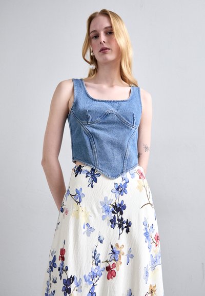 Denim crop top with a square neckline and stitched detailing, paired with a floral-patterned, flowing skirt in pastel colors.