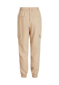 Pantalon cargo beige texturé avec taille et poignets élastiques, comprenant deux poches avant et deux poches latérales à rabat.