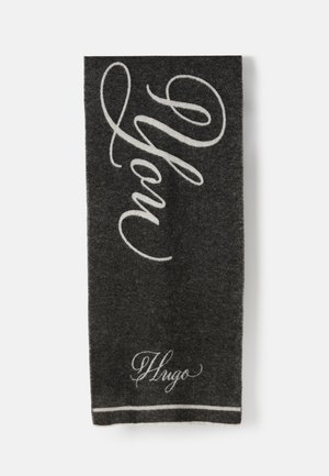 Écharpe gris foncé avec le logo "Hugo" en cursive blanche et un grand texte "Hugo" en script sur toute sa longueur.