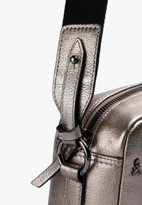 Bolso de hombro plateado metálico con una correa de cuero texturizado, acentos de hardware negro y cierre con cremallera. Presenta un detallado e interesante sistema de sujeción de la correa.