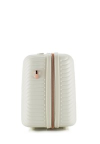 Harde koffer in off-white met horizontale groeven, roségouden rits en een enkele ritslip. Beschikt over kleine voetjes voor stabiliteit.