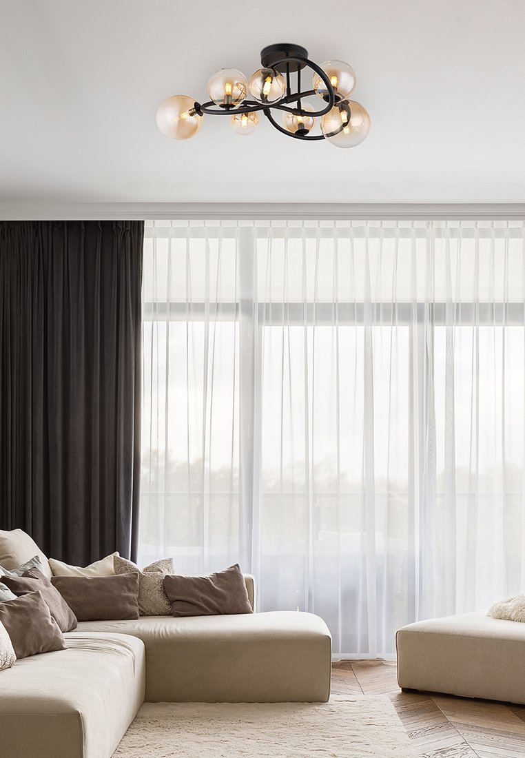 Schwarzer Metalllüster mit sechs klaren Glasglobes, der eine organische Form und sanftes Licht ausstrahlt, hängt von einer weißen Decke.