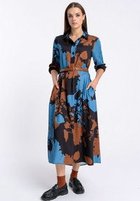 Sukienka z długim rękawem w niebieskie, czarne i brązowe kwiaty, z zapięciem na guziki z przodu, pasek w talii oraz kieszeniami po bokach; wykonana z gładkiego materiału.