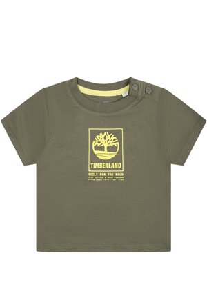 T-shirt en coton vert olive à manches courtes, encolure ronde, imprimé logo jaune avec un arbre et du texte à l'avant, deux boutons pression sur l'épaule.