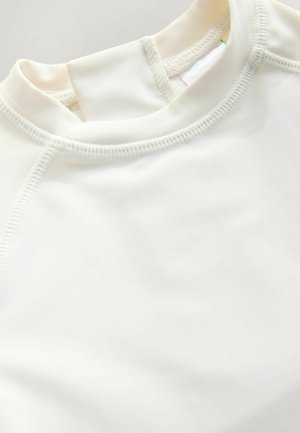 Biely športový top s okrúhlym výstrihom, hladkou textúrou a kontrastným prešívaním. Dizajn zahŕňa raglánové rukávy pre plnú pohyblivosť.