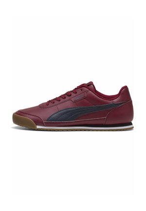 Chaussure de sport bordeaux à profil bas avec bande latérale noire, fermeture à lacets et semelle en caoutchouc marron sur fond blanc.