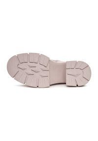 Semelle d'une basket comportant du caoutchouc rose clair avec des crampons et rainures profondes pour l'adhérence, un bout arrondi et une zone lisse et plate au niveau du talon.