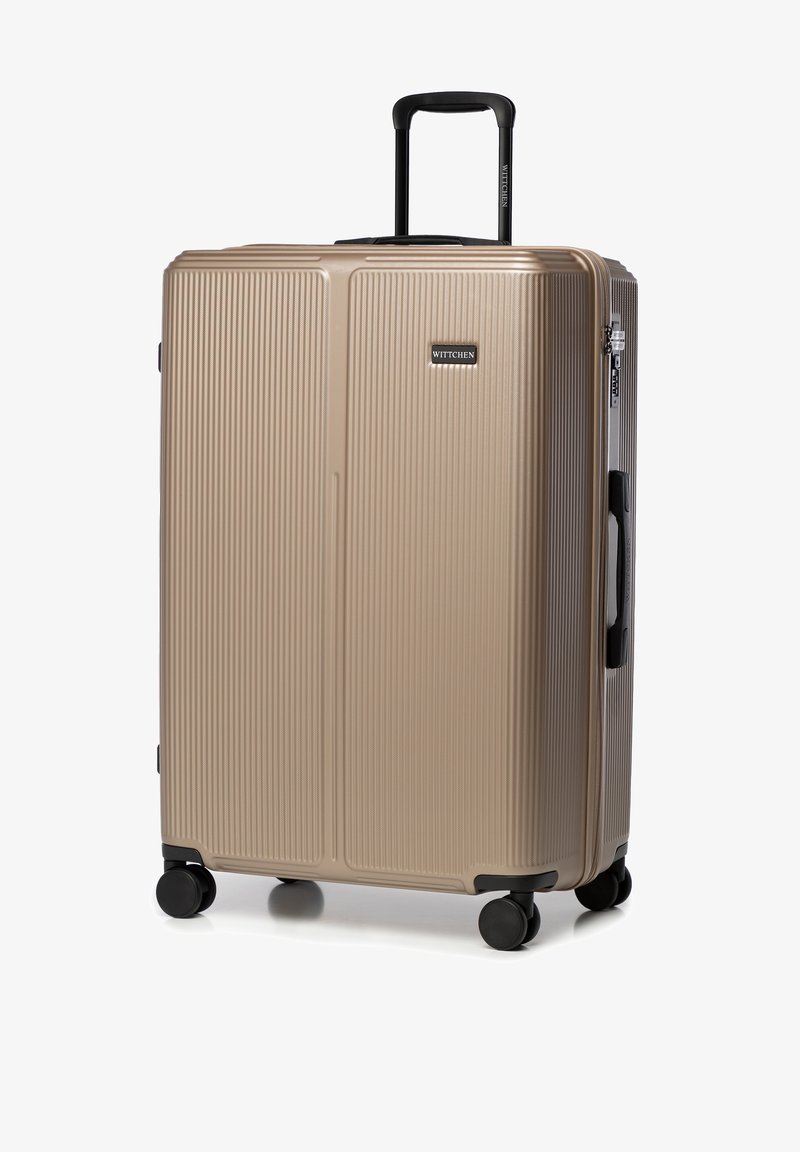 Valise en polycarbonate doré avec texture à rainures verticales, poignée rétractable, poignées latérales et quatre roues noires pour plus de mobilité.