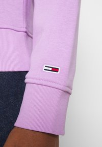 Ljuslila sweatshirtärm i bomullsmix med ribbad manschett och broderad logotyp i röd, vit och blå längst ner.