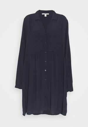 Robe-chemise à manches longues bleu marine foncé avec col et deux poches poitrine, coupe ample et tissu léger.