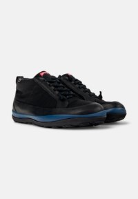 Zapatos negros con una combinación de materiales suaves y texturizados. Diseño de cordones con acentos azules en la suela y un collar acolchado para mayor comodidad.