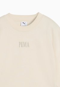 Cremefarvet bomulds-sweatshirt med ribbet crew neck. Har det broderede "PUMA" logo i en matchende farve på fronten.