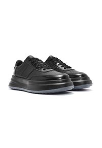 Zapatillas negras con parte superior de cuero suave, puntera perforada y suela de goma gruesa. Presenta cordones planos y un panel texturizado en los lados.