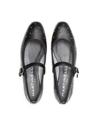 Zapatos planos de cuero negro con punta redondeada, adornados con tachuelas plateadas y una correa con hebilla. Textura suave con una plantilla acolchada.