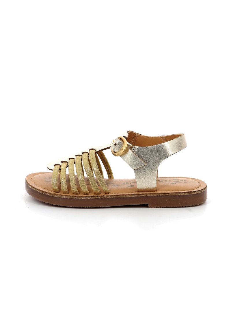 Sandale métallique dorée à lanières avec une semelle marron, dotée d'une fermeture à boucle et d'un design plat. Les lanières sont disposées en motif à lattes.