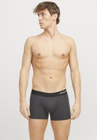 Dunkelgraue Herren-Boxershorts mit einem schwarzen Bund, der über weißen Logo-Text verfügt. Glatter Stoff, enganliegendes Design und mittellange Oberschenkellänge.