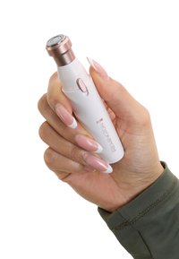 Remington groomingtool, witte behuizing, roségouden accenten, ronde scheerkop, ergonomisch ontwerp, vastgehouden in een hand met lange, verzorgd gemanicuurde nagels.