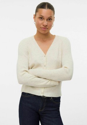 Crèmekleurige geribbelde cardigan met lange mouwen, V-hals en knoopsluiting. Zachte textuur en aangesloten ontwerp. Draagbaar over donkere jeans.