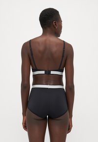 Conjunto de soutien preto e roupa interior de cintura alta com alças ajustáveis e uma ampla faixa elástica. Textura suave e design minimalista.