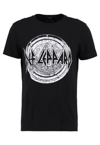 Musta puuvillapaita, jossa on suuri, pyöreä vintage-tyylinen graafinen kuva, jossa lukee "Def Leppard" valkoisella kuluneella fontilla.