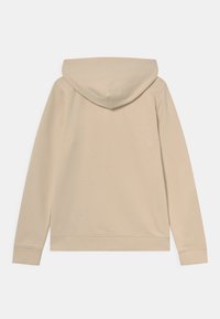 Sudadera beige con capucha ajustable, puños y dobladillo acanalados. Tela suave, textura lisa, sin logotipos ni patrones visibles en la parte posterior.