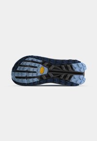 Semelle de chaussure de trail running avec des crampons multidirectionnels, en caoutchouc noir et bleu texturé, et un logo Vibram jaune distinct au centre.