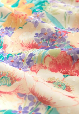 Leichter Blumenstoff mit großen pinken und roten Blumen, kleineren lila Blüten und einem cremefarbenen Hintergrund mit feiner Textur und Mustern.